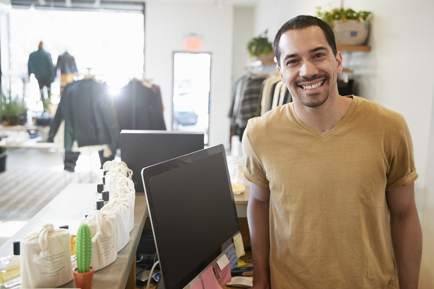 Male assistant smiling behind the counter in a clothes store