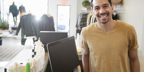 Male assistant smiling behind the counter in a clothes store